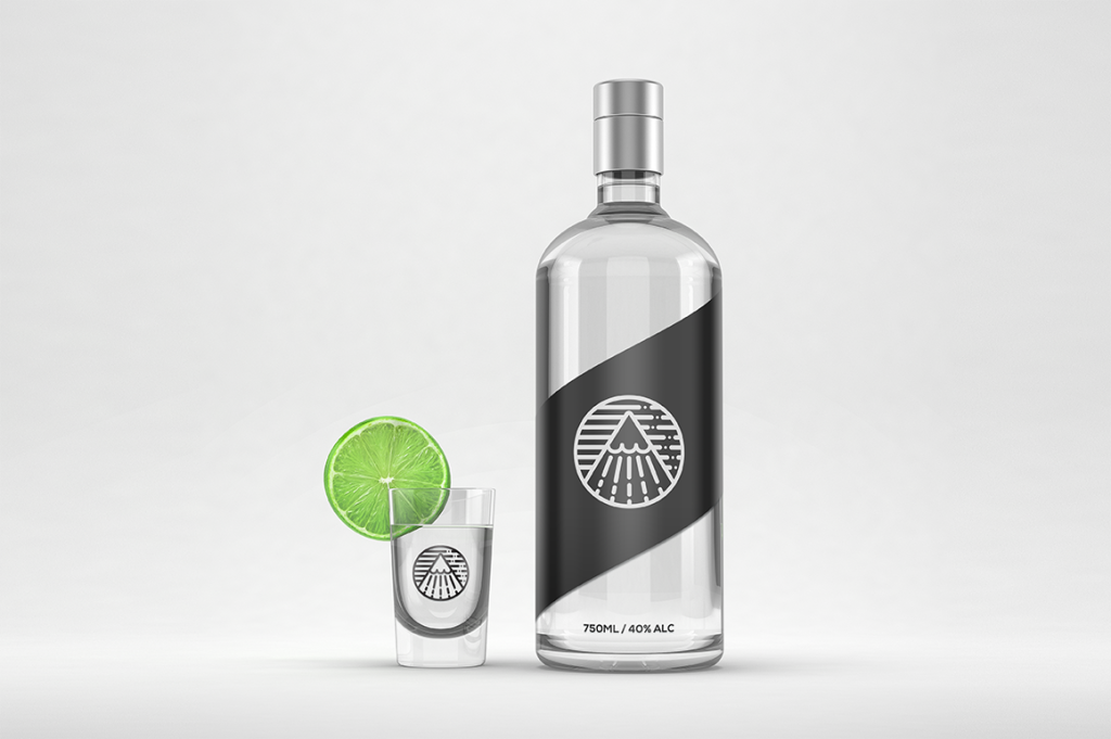 Transparent glass bottle of alcool with black label and a glass with green lemon slice on the side